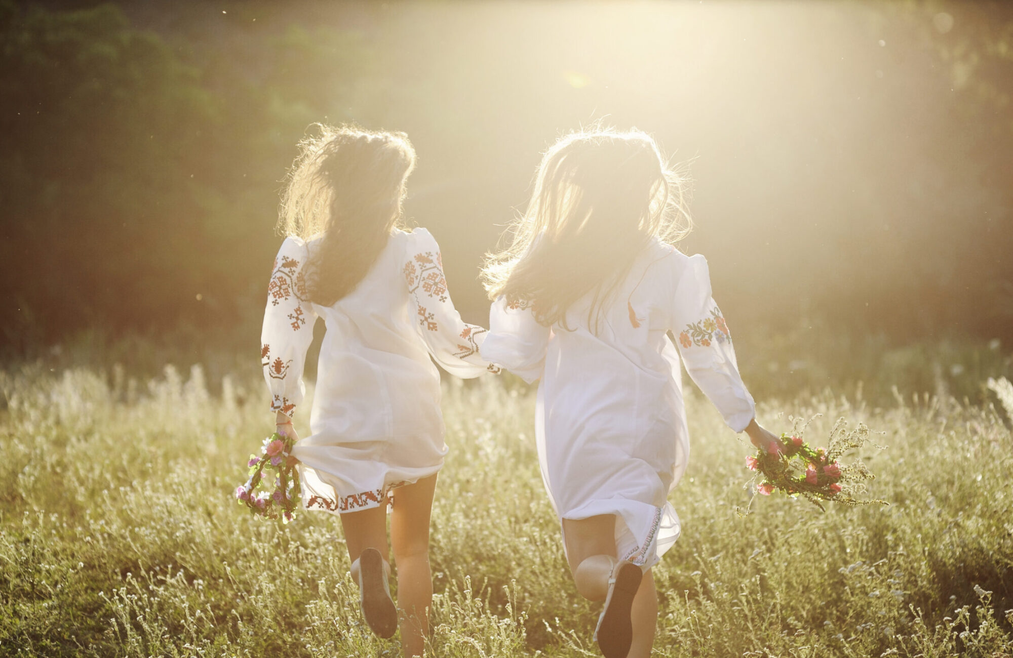Deux filles portant des couronnes d'été courant à travers une prairie d'été